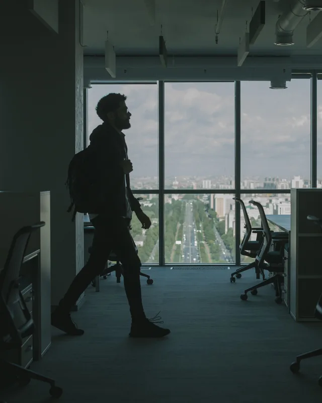 Un collaborateur traverse un plateau de bureaux, la ville en arriere-plan